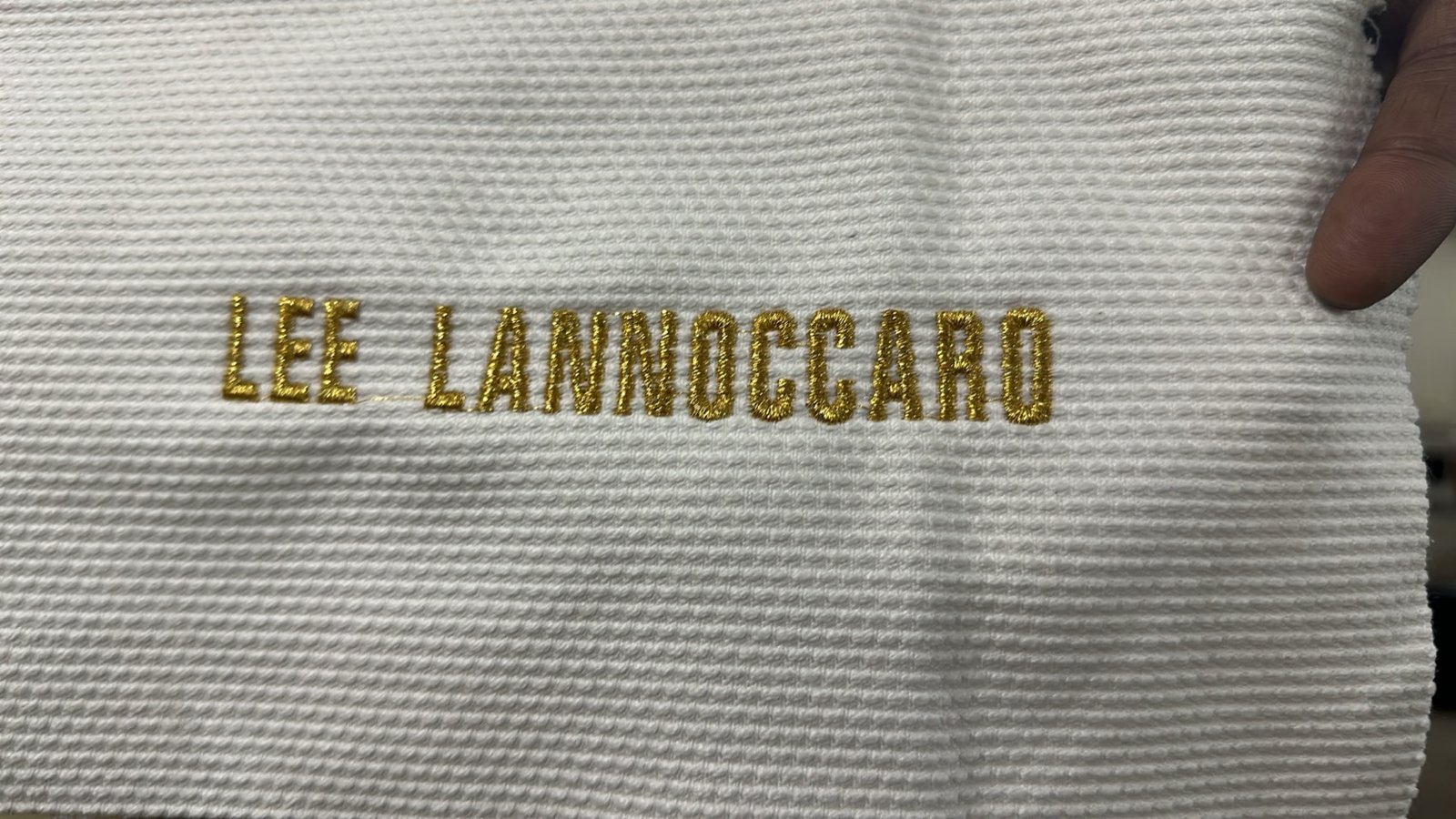 Personalised gold-thread name embroidery on a white pearl-weave BJJ gi